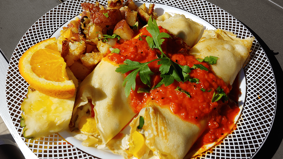 A closer look at the breakfast burrito with potatos, orange slice and Element 79 wine.